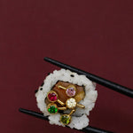 Close-up of multiple brightly colored stone earrings pictured in a piece of sushi