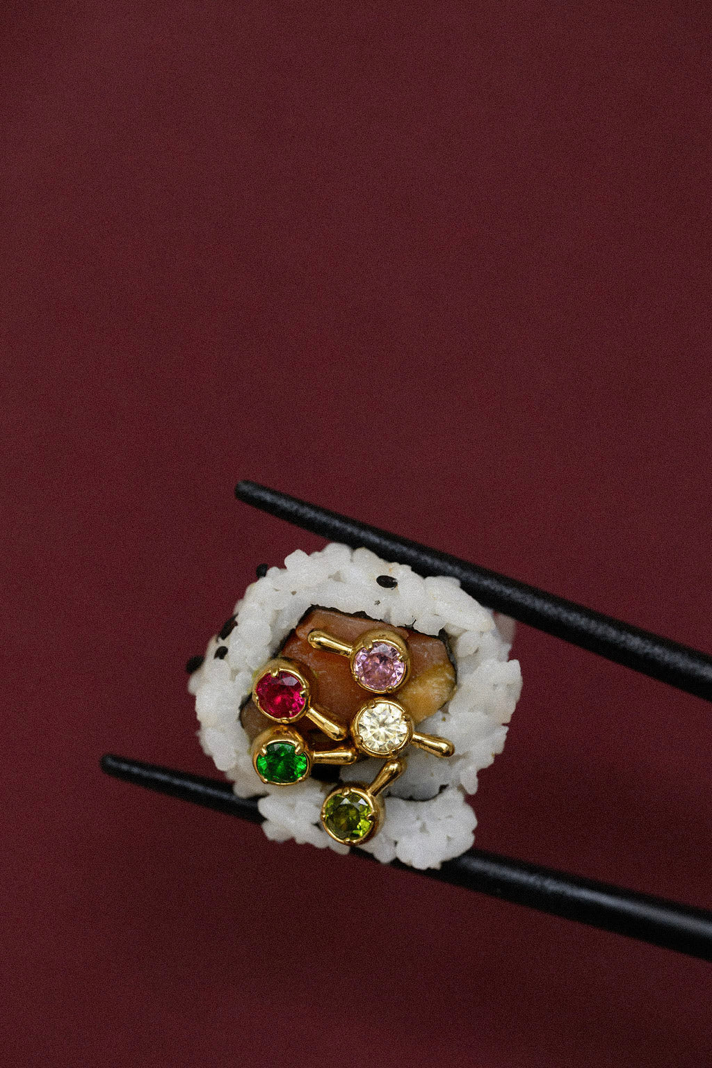 Close-up of multiple brightly colored stone earrings pictured in a piece of sushi