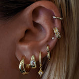 Close-up of an ear with multiple gold earrings
