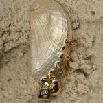 Gold earrings with diamonds on a shell against a textured beige background