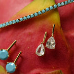 Gold earrings with gemstones on a red flower background