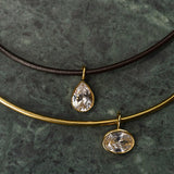 Two necklaces with teardrop-shaped pendants on a dark stone surface