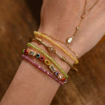 Close-up of a wrist wearing multiple beaded bracelets and a necklace on a wooden surface.