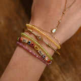Close-up of a wrist wearing multiple beaded bracelets and a necklace on a wooden surface.