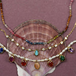 Stack of colorful necklaces on a shell with a purple background