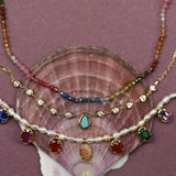 Stack of colorful necklaces on a shell with a purple background