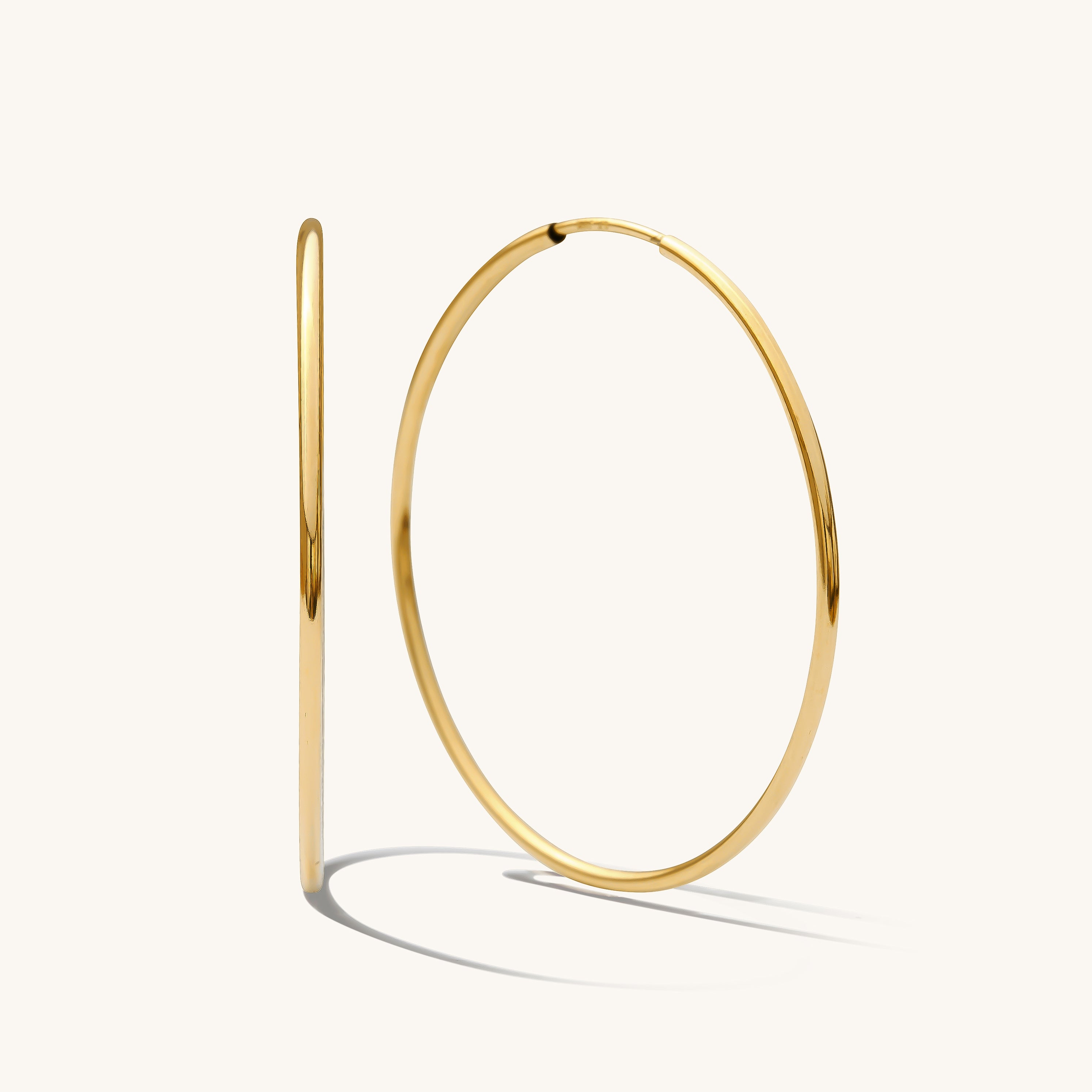 Close up of thin gold hoops on a white background 