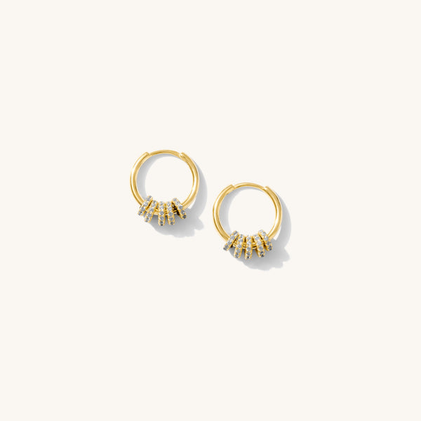 Close up of gold hoops with crystal charms on a white background 