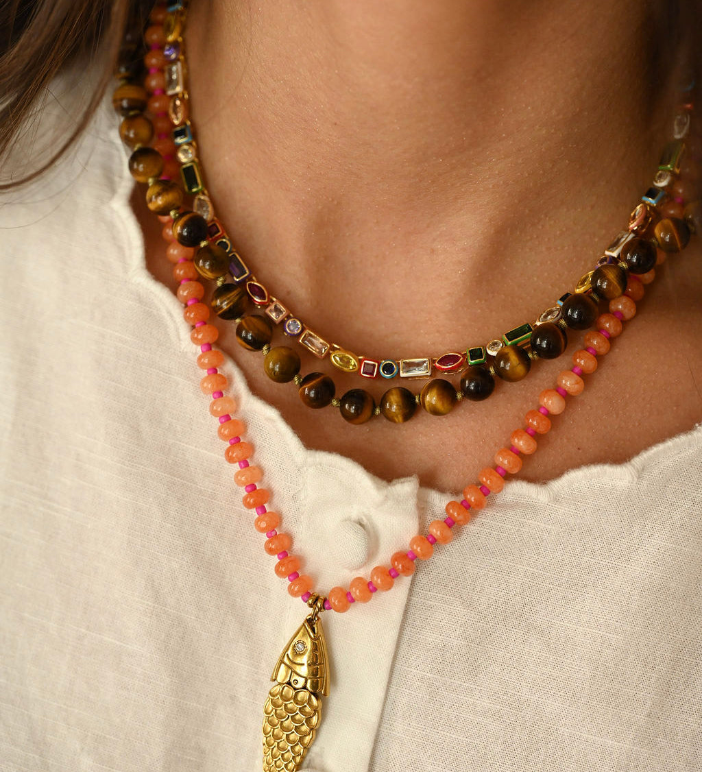 Necklace with a gold fish pendant on a white shirt