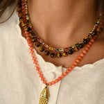 Necklace with a gold fish pendant on a white shirt
