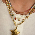 Close-up of a gold chain necklace with a star pendant on a white background