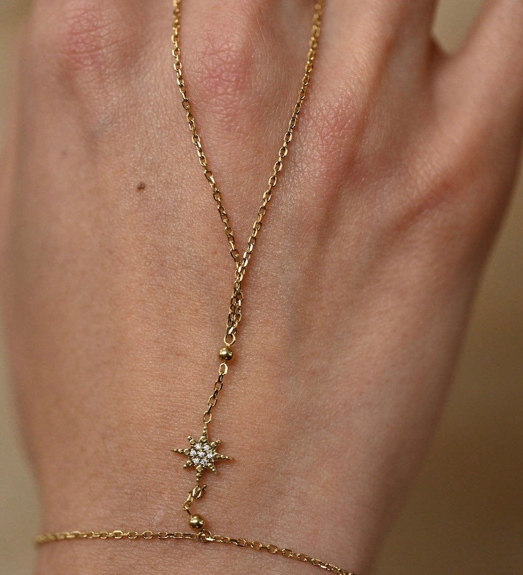Gold bracelet with star design on a wrist against a neutral background