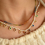 Necklace with colorful beads and pearls worn by a person in a cream-colored garment.