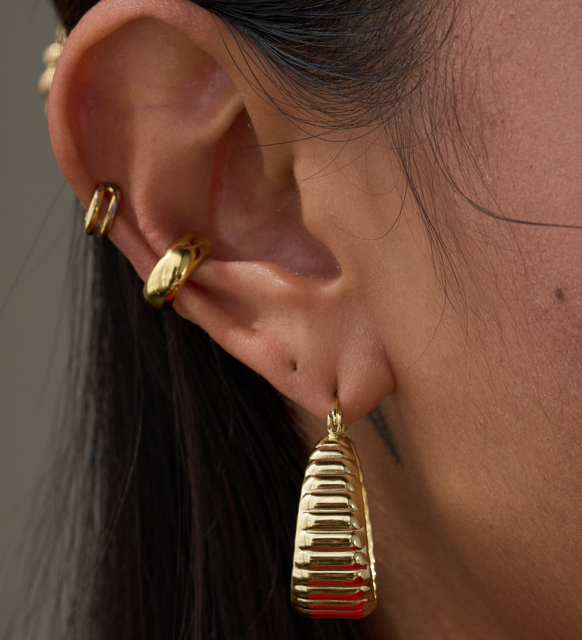 Close-up of an ear with multiple gold earrings 