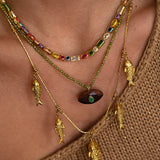 Close-up of a person wearing a gold necklace with fish charms and colorful beads.