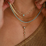 Close-up of a person wearing multiple gold and turquoise necklaces.