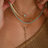 Close-up of a person wearing multiple gold and turquoise necklaces.