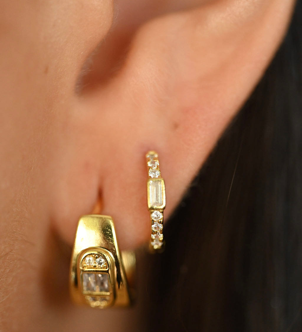 Close-up of gold hoop earrings worn by a person.