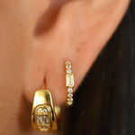 Close-up of gold hoop earrings worn by a person.