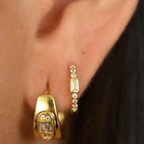 Close-up of gold hoop earrings worn by a person.