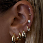 Close-up of an ear with gold earrings and hair details