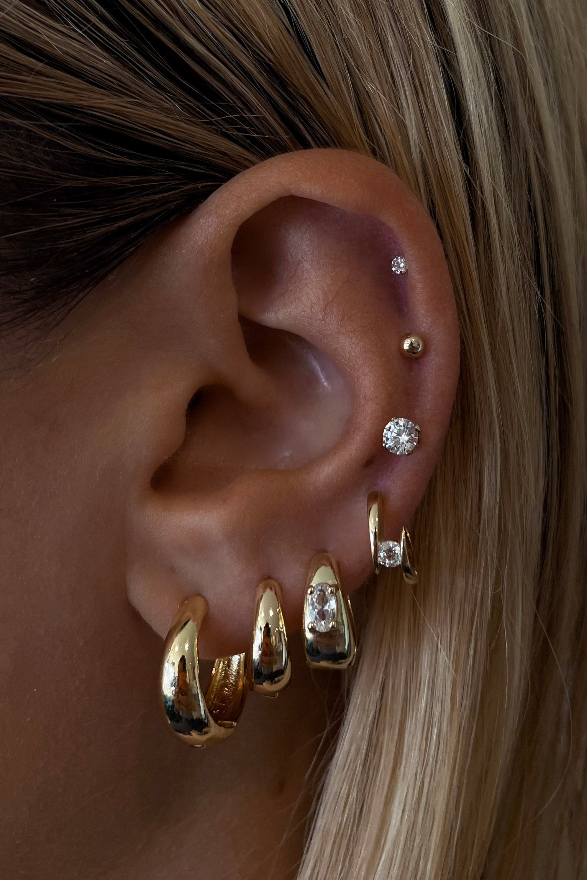 Close-up of an ear with gold earrings and hair details