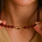 Close-up of a person wearing a brown beaded necklace with a gold clasp.