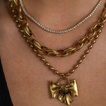 Gold chain necklace with a bow pendant on a person's neck