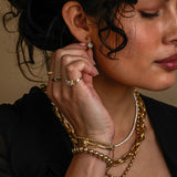 Woman wearing gold jewelry including a necklace, bracelet, and ring.