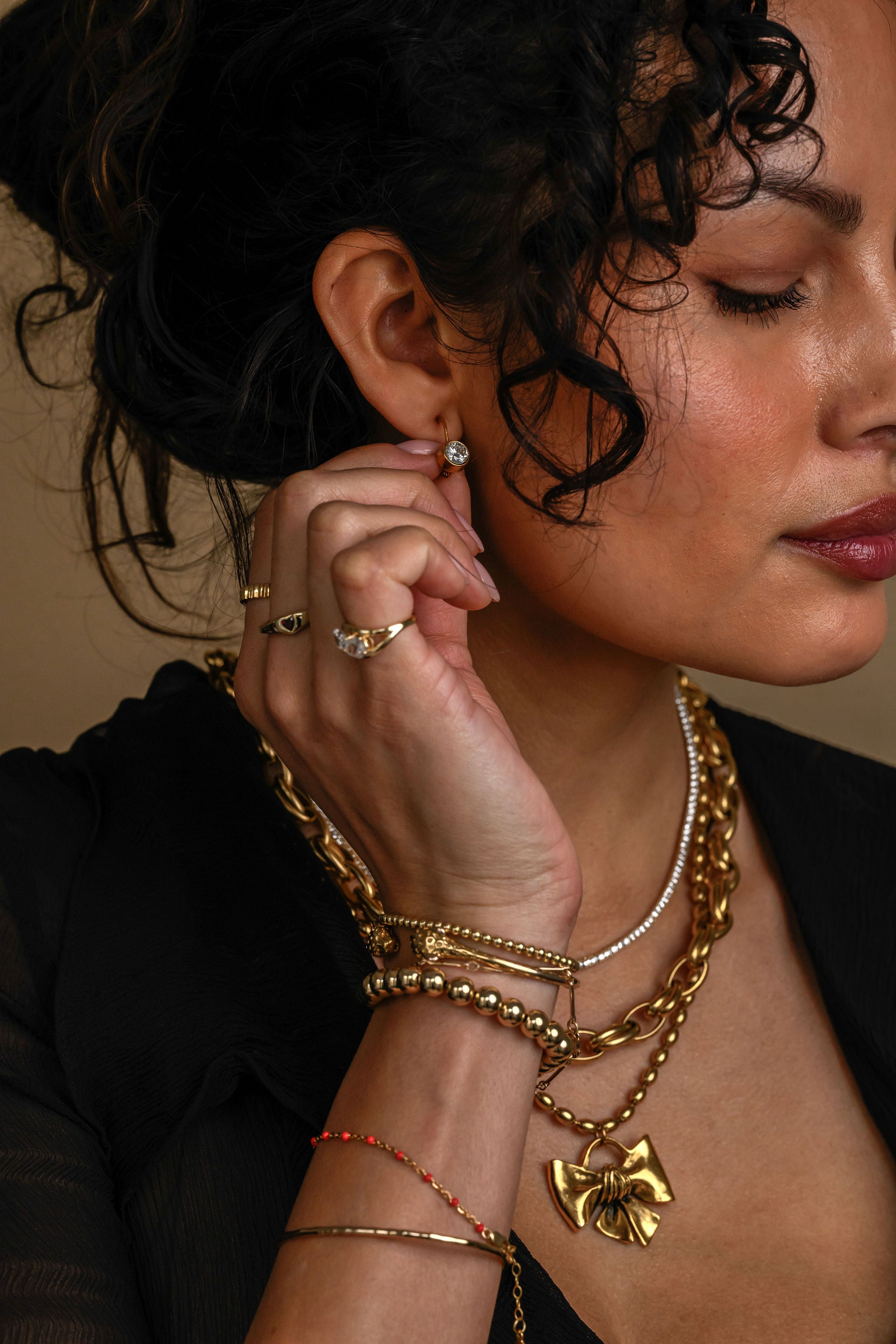 Woman wearing gold jewelry including a necklace, bracelet, and ring.