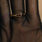 Gold ring with a red gemstone on a textured brown fabric background