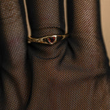 Gold ring with a red gemstone on a textured brown fabric background