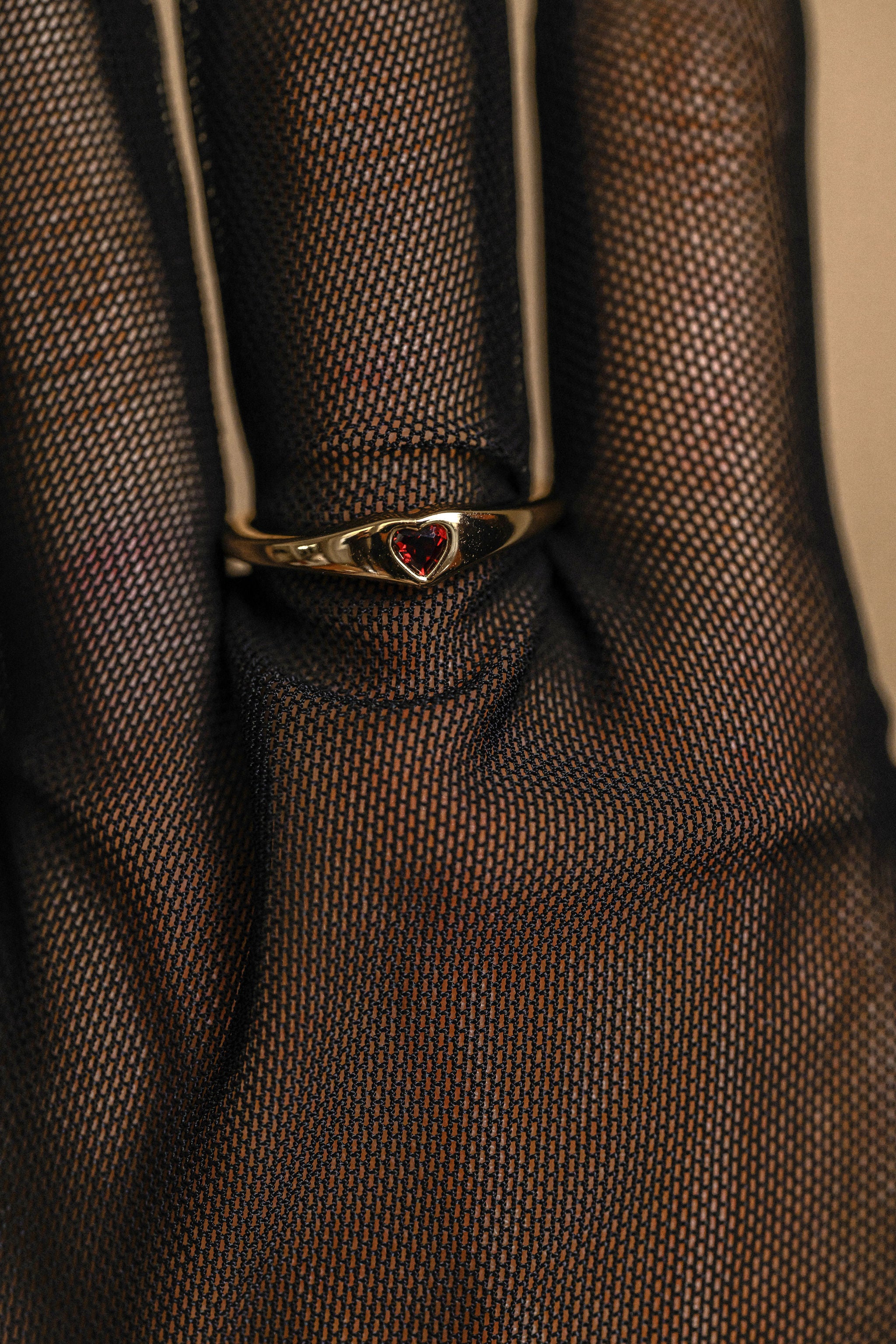 Gold ring with a red gemstone on a textured brown fabric background