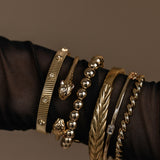 Collection of gold bracelets on a dark fabric background