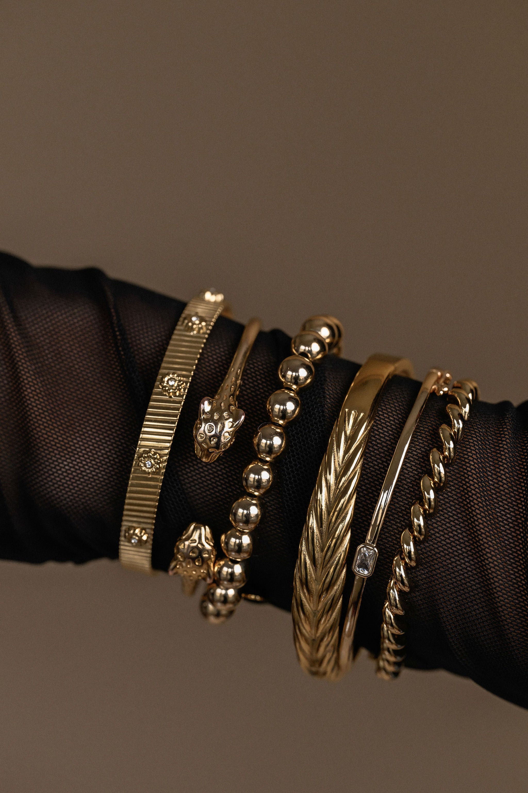 Collection of gold bracelets on a dark fabric background