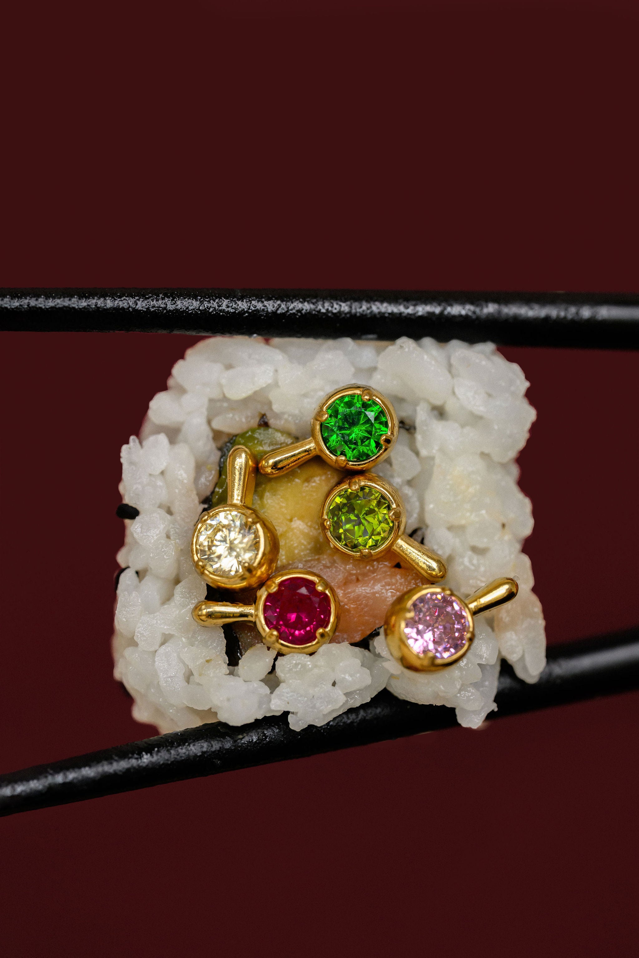 Close-up of multiple brightly colored stone earrings pictured in a piece of sushi