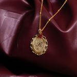 Gold necklace with a pendant on a maroon fabric background