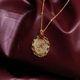 Gold necklace with a pendant on a maroon fabric background