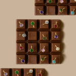 Three chocolate bars with each chocolate square featuring a brightly colored stone earring 