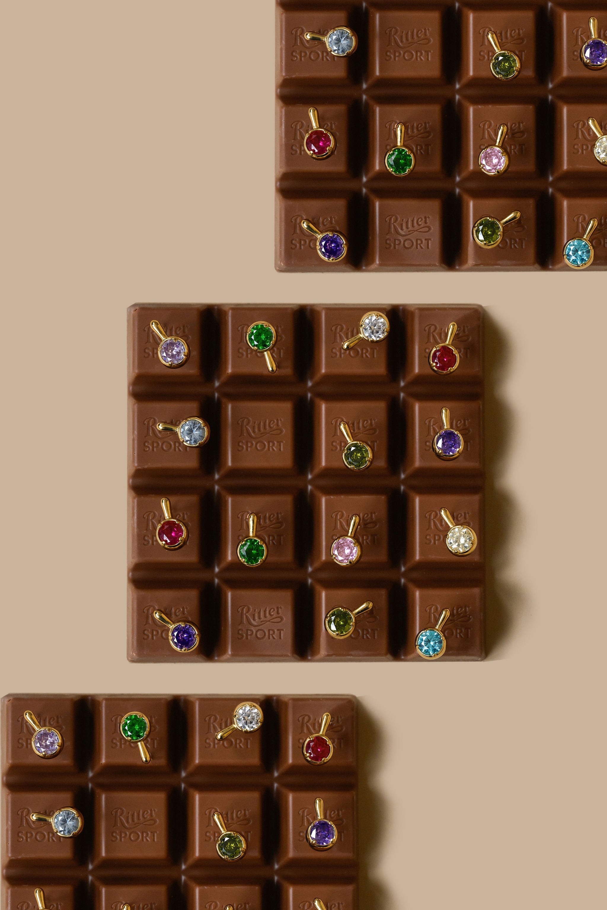 Three chocolate bars with each chocolate square featuring a brightly colored stone earring 