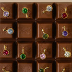 A chocolate bar with each square featuring a brightly colored stone earring 