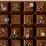 A chocolate bar with each square featuring a brightly colored stone earring 