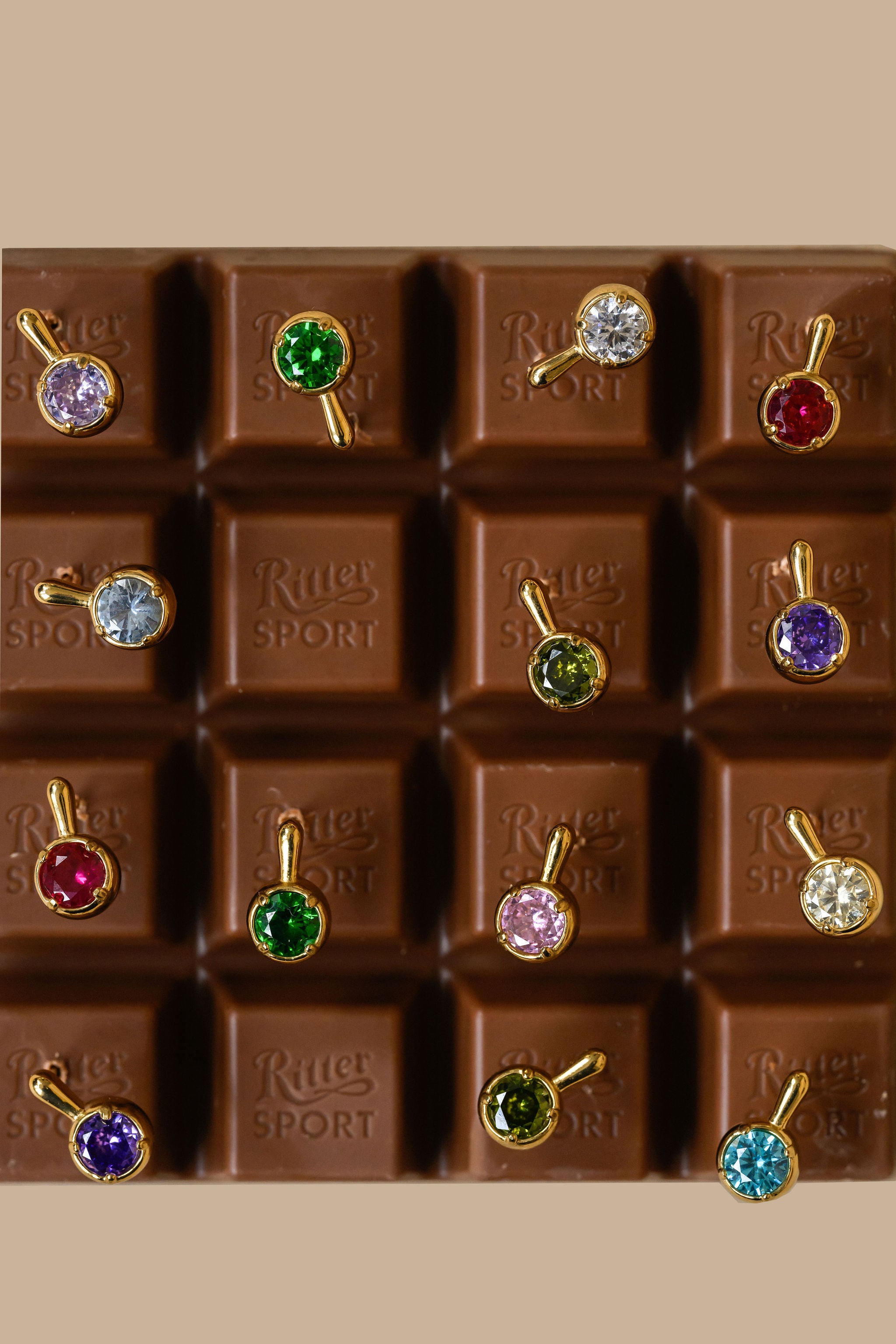 A chocolate bar with each square featuring a brightly colored stone earring 