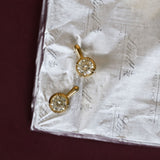 Close-up of stone earrings on a white paper with maroon background