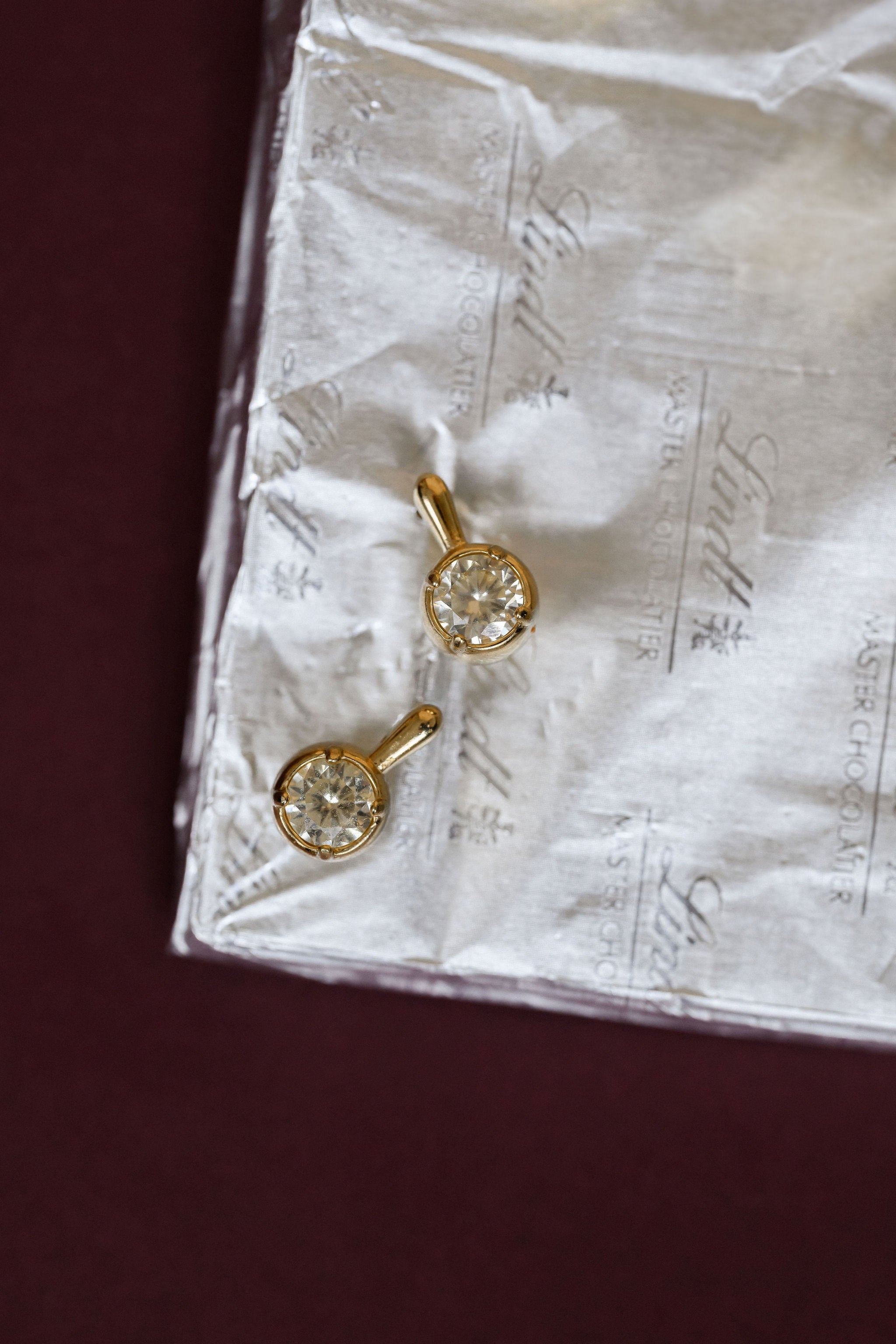 Close-up of stone earrings on a white paper with maroon background