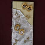 Set of gold earrings on a textured white card against a dark red background