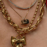 Gold chain necklaces with bow pendants on a person's neck