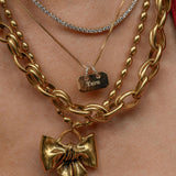 Gold chain necklaces with bow pendants on a person's neck