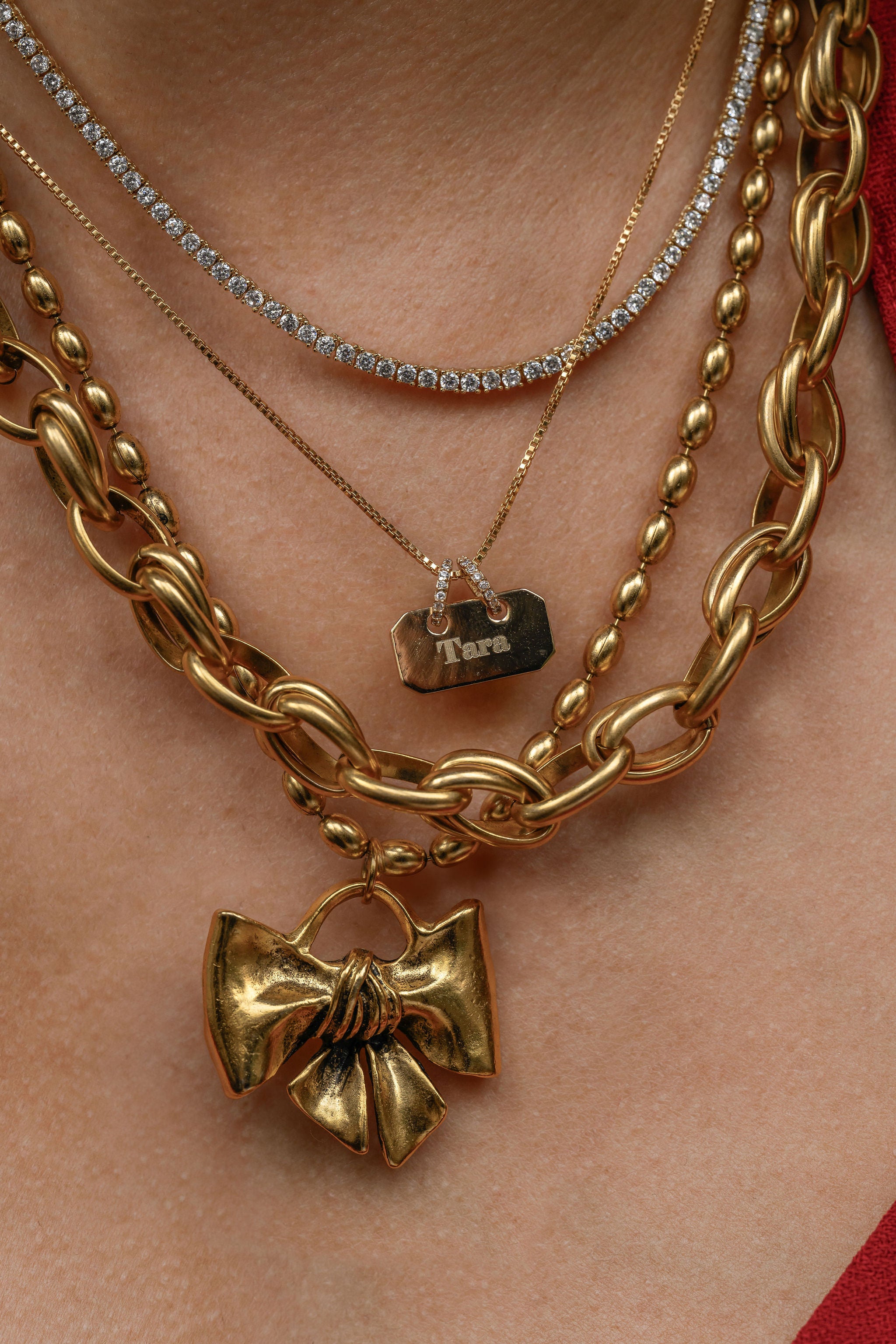 Gold chain necklaces with bow pendants on a person's neck