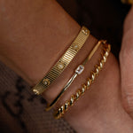 Gold bracelets on a wrist with a blurred background